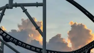 רכבת הרים מפלדה עם קרון בתוך לולאה כפולה על רקע שמיים כחולים